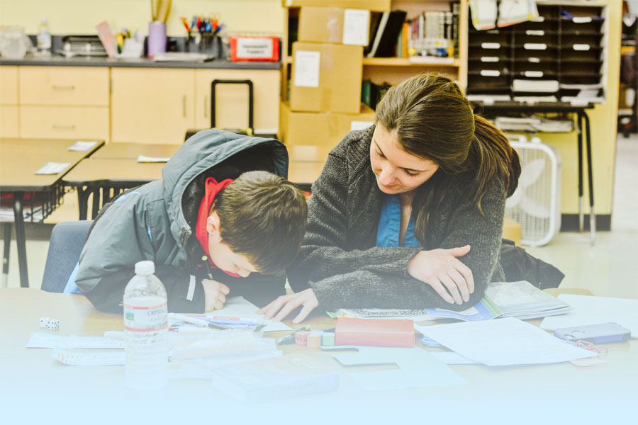 a graduate of Gordon College’s Master’s in education program working at an elementary school with a student.