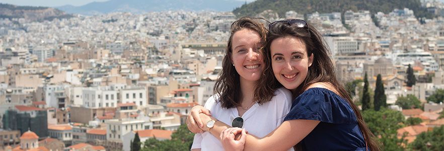 Two honors students hugging overlooking the city of Athens