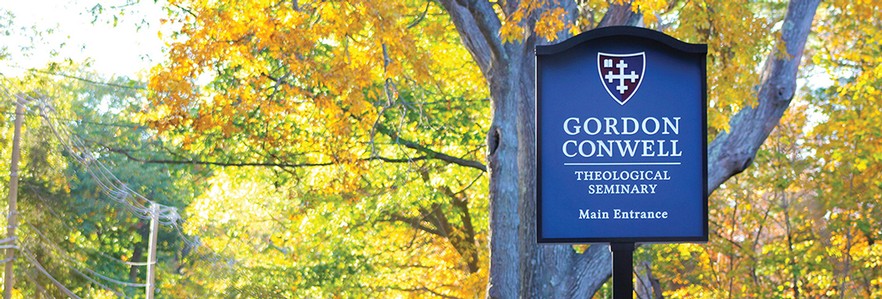 Blue and White Gordon-Conwell Theological Seminary sign in front of a leafy, fall landscape.